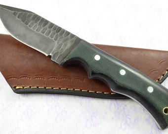 May include: A green and black handled knife with a hammered steel blade. The knife is in a brown leather sheath.