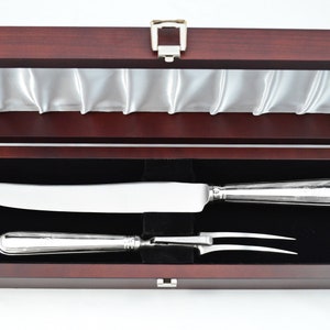 May include: A wooden box with a satin lining, containing a silver carving knife and fork set.