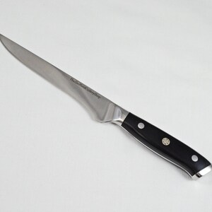 Könnte beinhalten: Ein Ausbeinmesser aus Edelstahl mit schwarzem Griff. Die Klinge ist gebogen und verjüngt sich zu einer scharfen Spitze. Der Griff hat drei Nieten und eine silberne Endkappe. Das Messer ist für präzises Schneiden konzipiert.