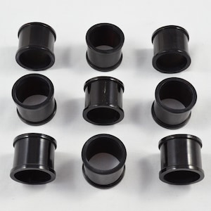 May include: Ten black rubber rings, each with a smooth, cylindrical shape. The rings are arranged in three rows on a white surface.