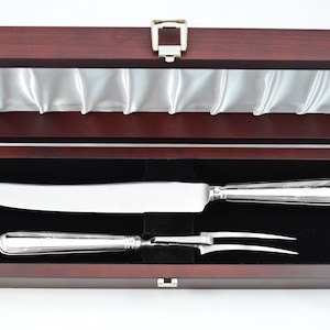 May include: A wooden box with a satin lining, containing a silver carving knife and fork set.