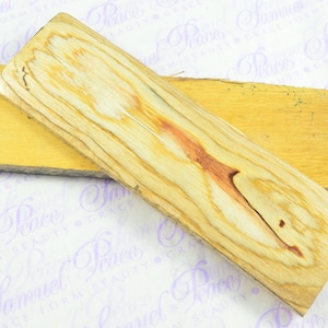 May include: Two pieces of wood, one with a light brown colour and the other with a light brown colour with reddish brown streaks. The wood is smooth and has a natural grain.