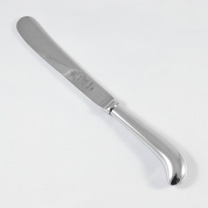 May include: A silver butter knife with a curved handle and the inscription "The Sanderson Trust" on the blade.