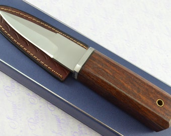 May include: A brown wooden handled knife with a leather sheath. The knife has a silver metal bolster and a brass ring on the handle.