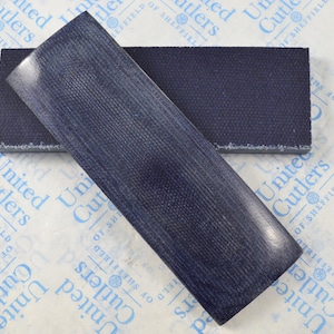 Può includere: Due placche per coltelli rettangolari, testurizzate, di colore blu scuro. Le placche sono realizzate in un materiale che ricorda il legno.