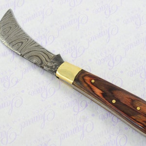 May include: A curved blade knife with a patterned steel blade and a wooden handle with brass accents.