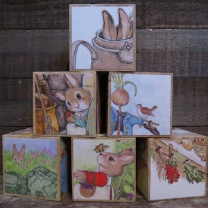 May include: A set of six wooden blocks featuring illustrations from the children's book "The Tale of Peter Rabbit". Each block depicts a different scene from the story, including Peter Rabbit, a garden, a bird, and a rabbit in a watering can.
