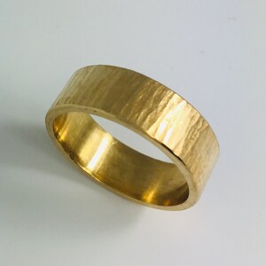 May include: A gold band ring with a hammered texture.