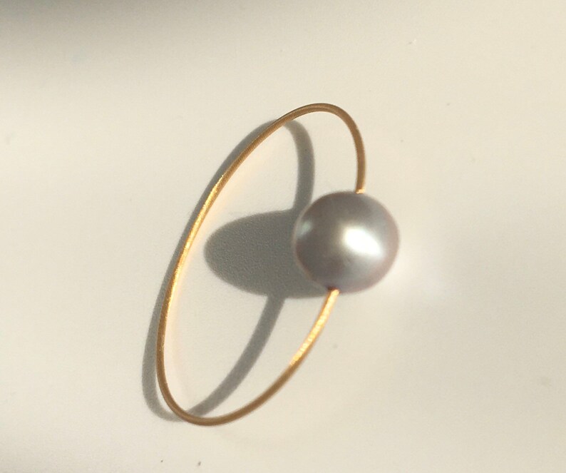 Smyckeset. 3 pärlringar, vita, grå och rosa på en tråd av guld. bild 3