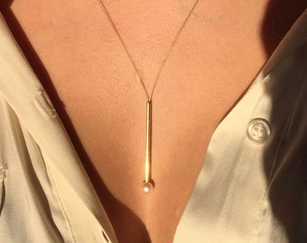 Pearl necklace. A freshwater pearl and a gold tube on a wire of gold. You can vary the lenght by yourself, by fixing the ends on a position.