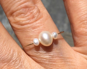 Sierlijke parelring. Witte zoetwaterparels op een draad van goud. Sierlijke ring Stapelbaar