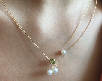 Collana di perle con peridoto. Perle d'acqua dolce con un peridoto in un ambiente su un filo d'oro. Collana Lariat per tutti i giorni