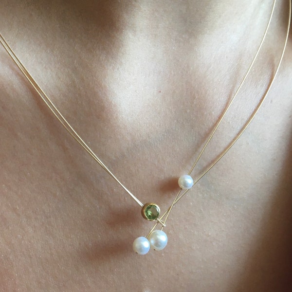 Pearl necklace with peridot. Freshwater pearls with a peridot in a setting on a wire of gold.