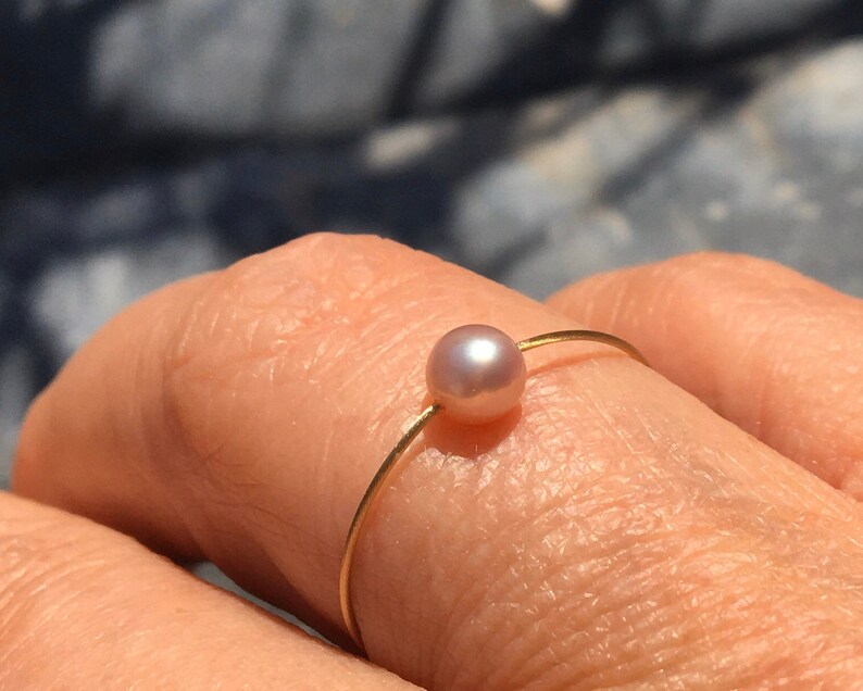 Smyckeset. 3 pärlringar, vita, grå och rosa på en tråd av guld. bild 4