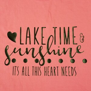 May include: A pink t-shirt with a black graphic that says "Lake Time & Sunshine. It's all this heart needs."