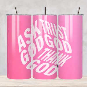 May include: A set of three pink stainless steel tumblers with silver straws. Each tumbler features the white text "ASK GOD TRUST GOD THANK GOD" in a circular design. The tumblers are designed for cold beverages.