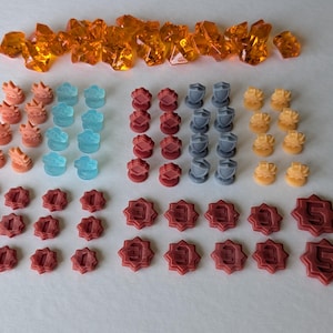 May include: An assortment of game pieces in various colors. Includes orange crystal-like shapes, coral-colored flame-like pieces, light blue water-like pieces, red and gray shield-like pieces, and yellow star-like pieces. Also, red star-shaped pieces with numbers.