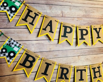 Könnte beinhalten: Ein braunes und gelbes Banner mit den Worten "HAPPY BIRTHDAY" in schwarzen Buchstaben. Das Banner ist mit grünem und schwarzem kariertem Stoff und grünen Traktor-Illustrationen verziert.