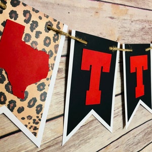 May include: A black and red banner with the letters "TTU" in red and a white outline. The banner is decorated with a leopard print pattern and a red outline of the state of Texas.