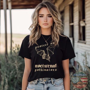 May include: A black t-shirt with a gold graphic of a bat and the text "protect our nocturnal pollinators".