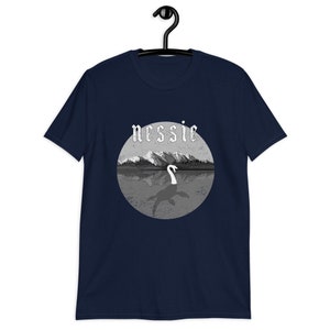 May include: A navy blue t-shirt with a graphic of a gray and white Loch Ness Monster with the word "nessie" in a gothic font above the monster.