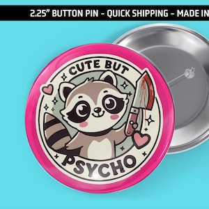 May include: A 2.25 inch button pin with a pink background. The pin features a cartoon raccoon holding a bloody knife with the text "Cute But Psycho" in a white circle.