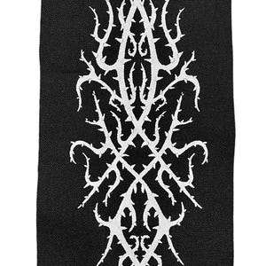 May include: White embroidered patch with a thorny, intricate design on a black fabric background.