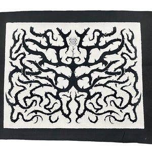 May include: Black and white embroidered patch with a symmetrical design of thorny branches and a flower in the center.