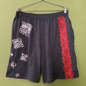 May include: Gray sweatpants with a red and black geometric pattern on the right leg and white and black geometric patterns on the left leg.