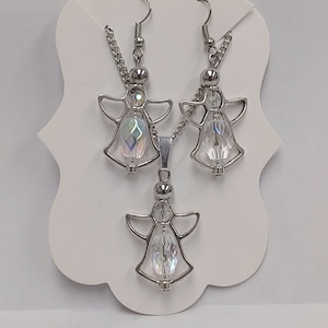 May include: A silver angel pendant necklace and matching earrings with clear iridescent crystal accents.