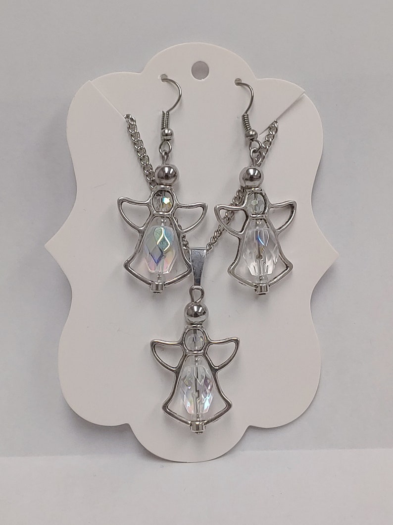 May include: A silver angel pendant necklace and matching earrings with clear iridescent crystal accents.