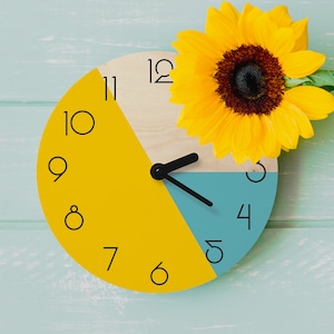 May include: A yellow and blue clock with black numbers and hands. The clock is decorated with a yellow sunflower.