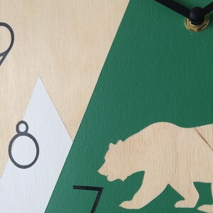 Close-up view showing the high-quality finish of the green mountain and animal silhouettes on a natural wooden base.