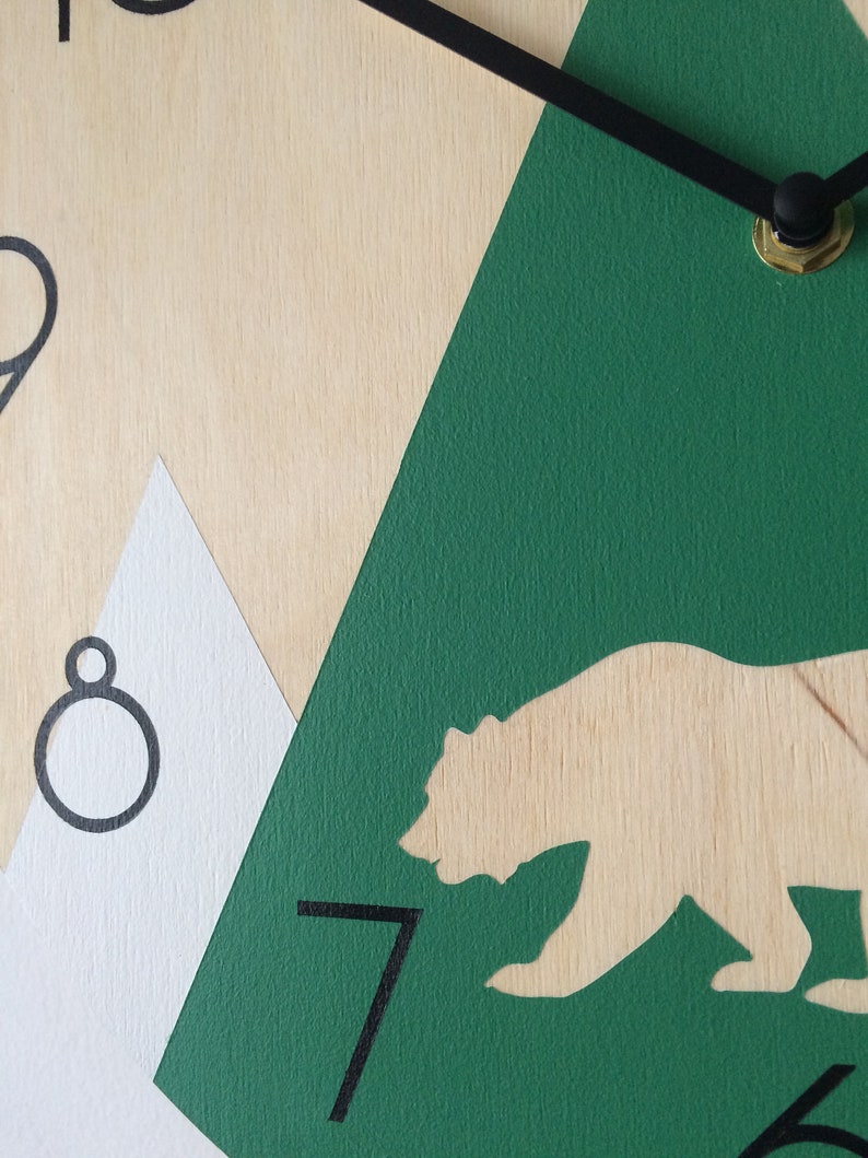 Close-up view showing the high-quality finish of the green mountain and animal silhouettes on a natural wooden base.
