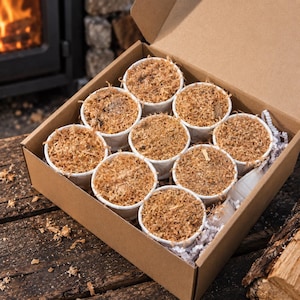 May include: A brown cardboard box containing nine white paper cups filled with brown wood shavings. The cups are arranged in a three-by-three grid, and the box is filled with white shredded paper packing material to secure the cups in place.