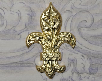 Puede incluir: Un diseño de flor de lis de metal dorado con detalles intrincados. El diseño es un símbolo tradicional de la realeza y se utiliza a menudo en el arte decorativo.