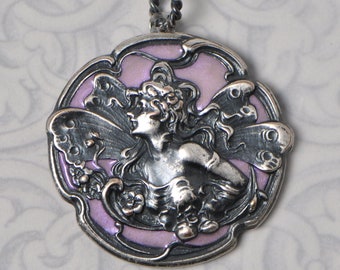 May include: A silver pendant with a detailed design of a fairy with wings, set against a lavender enamel background.