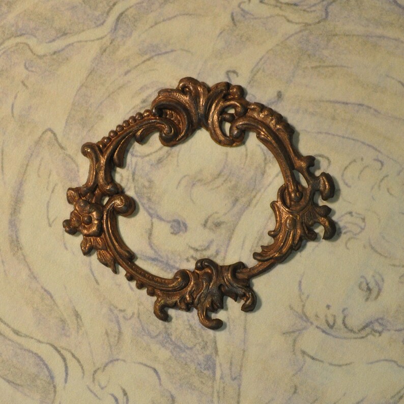 May include: A decorative metal frame with an ornate design. The frame is made of brass and has a gold finish. It is a vintage style frame with a delicate and intricate design.