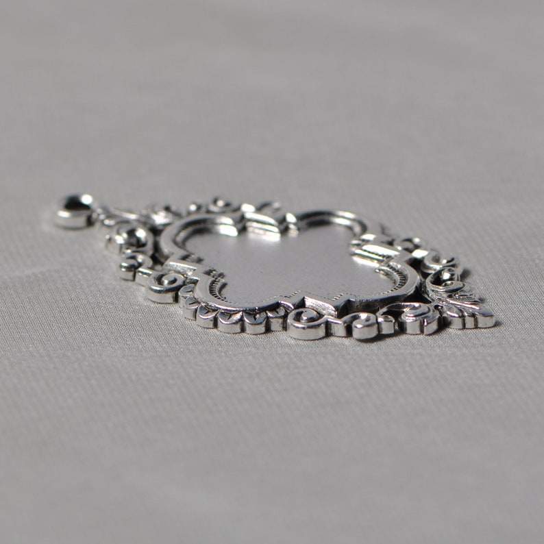 May include: A silver pendant with an ornate, intricate design. The pendant is shaped like a teardrop and has a detailed, filigree pattern.