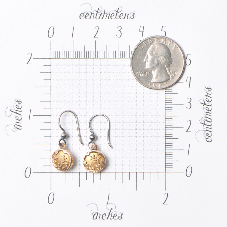 May include: A pair of gold and silver dangle earrings with a floral design. The earrings are about 1 inch long and are shown next to a US quarter for size comparison.