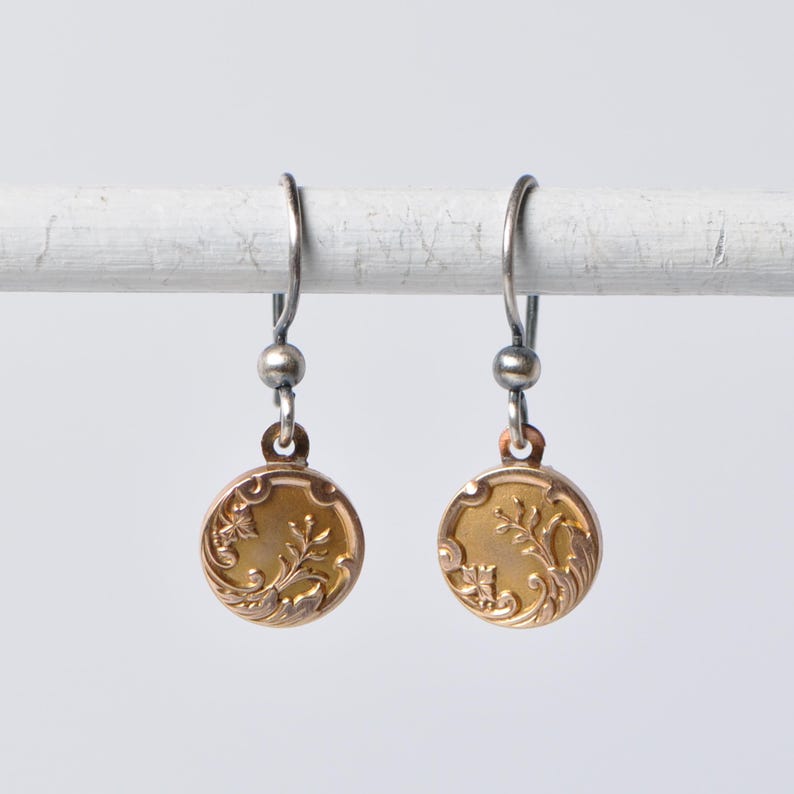 May include: A pair of gold earrings with a floral design. The earrings are made of silver and have a delicate, vintage look.
