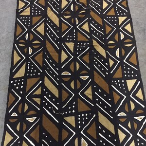 May include: A brown and white patterned fabric with geometric shapes and dots. The fabric is woven and has a rough texture.