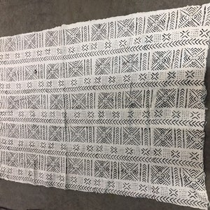 May include: A white fabric with a black geometric pattern. The pattern is made up of squares, diamonds, and triangles.