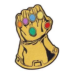 May include: A gold-colored embroidered patch of a hand wearing a gauntlet with six colorful gems. The gauntlet is a popular symbol from the Marvel Cinematic Universe.