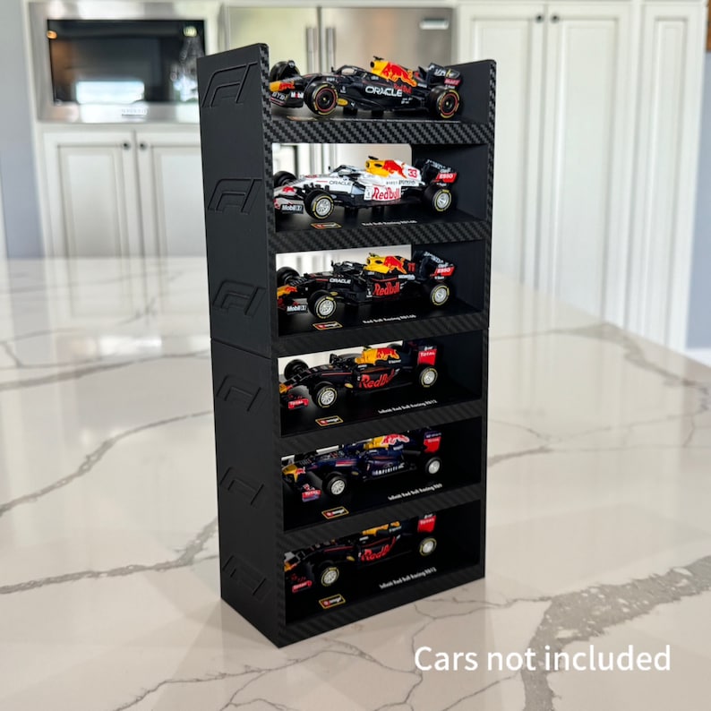 May include: Black Formula 1 car display stand with six shelves. Each shelf has a black carbon fiber pattern and is designed to hold a 1:18 scale model car. The stand is made of high-quality 3D printed plastic. Cars not included.