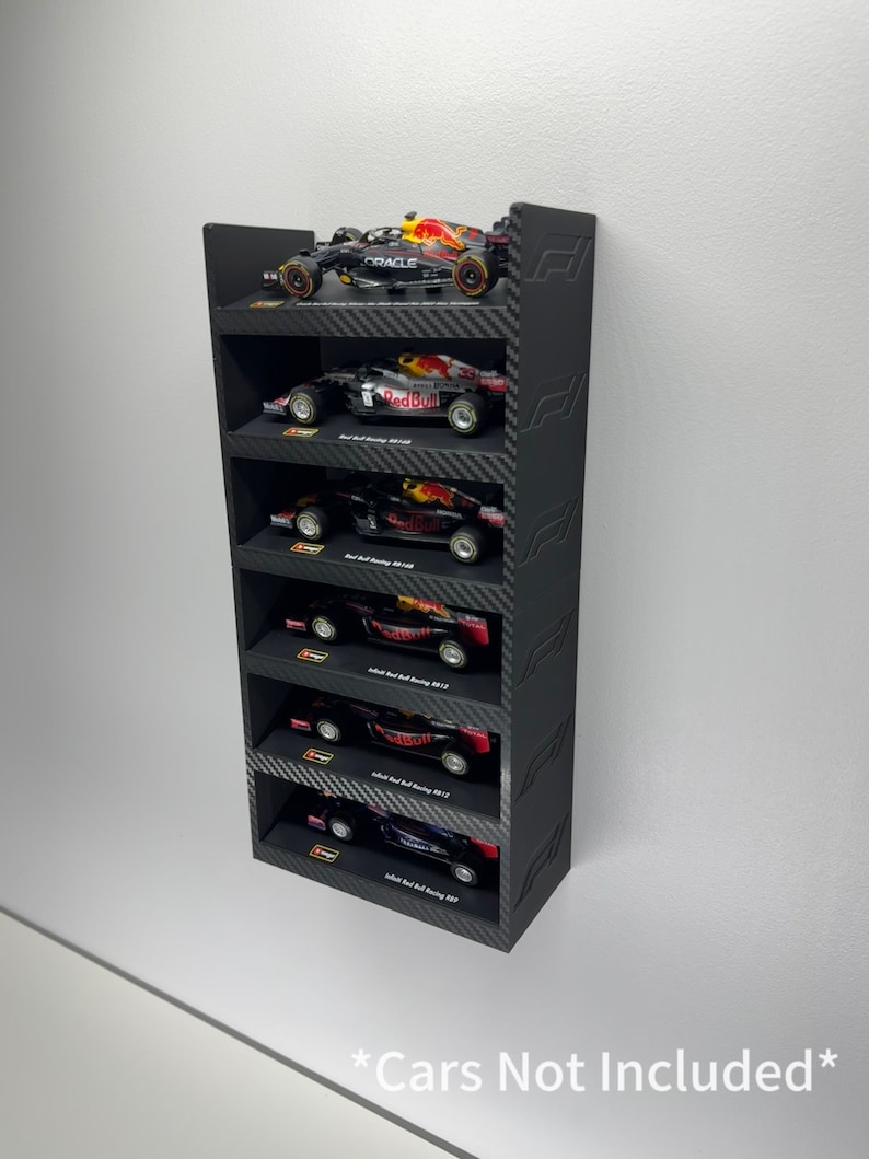 May include: Black wall shelf with six shelves for displaying miniature Formula 1 race cars. The shelves are made of black wood with a carbon fiber pattern. The shelf is labeled "*Cars Not Included*"
