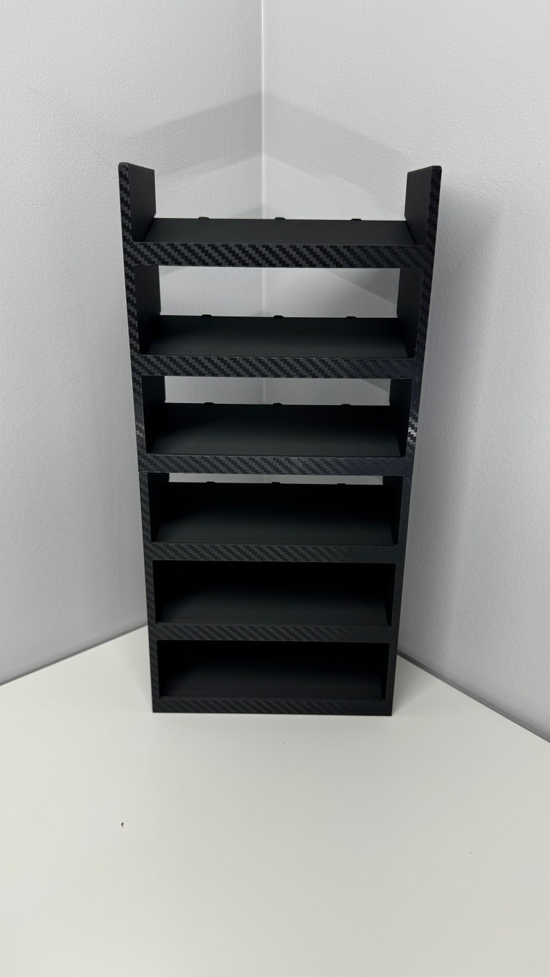 May include: A black, multi-tiered shelf unit with a carbon fiber pattern. The shelf unit is made of wood and has a modern design.