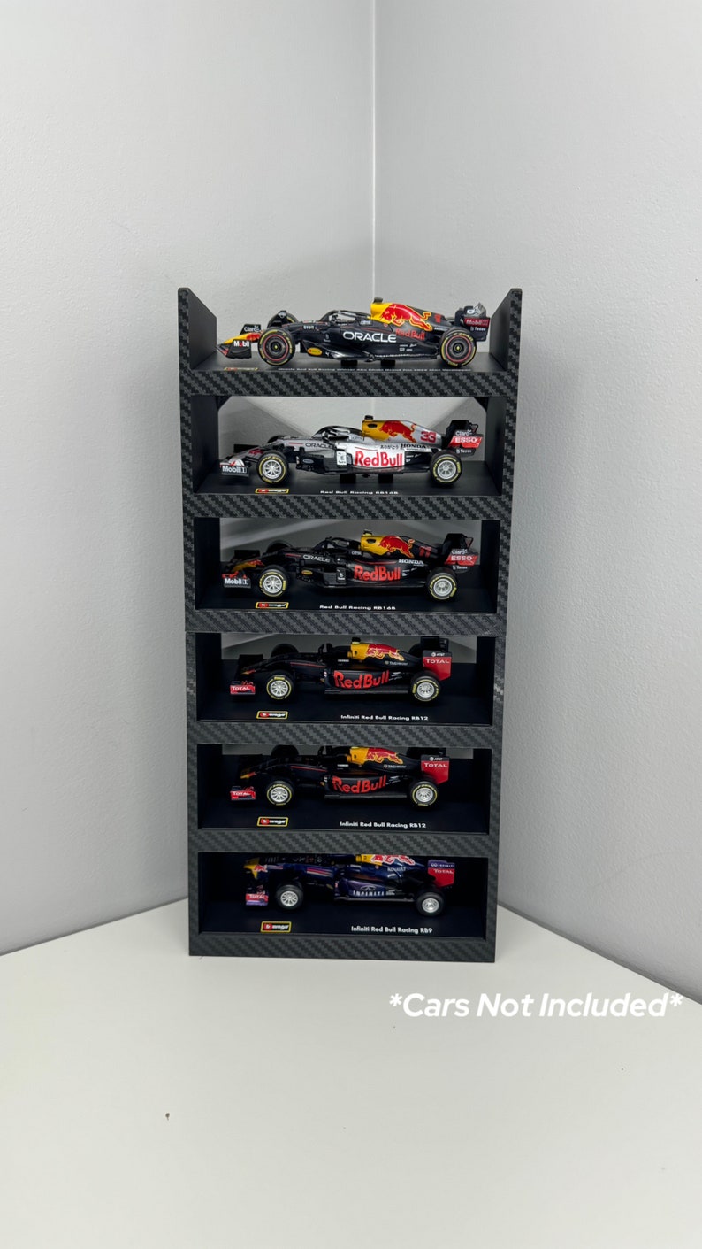 May include: A black and red Formula 1 race car display stand with six shelves. The shelves are made of a carbon fiber pattern material. The stand is designed to hold 1:18 scale model cars. *Cars Not Included*