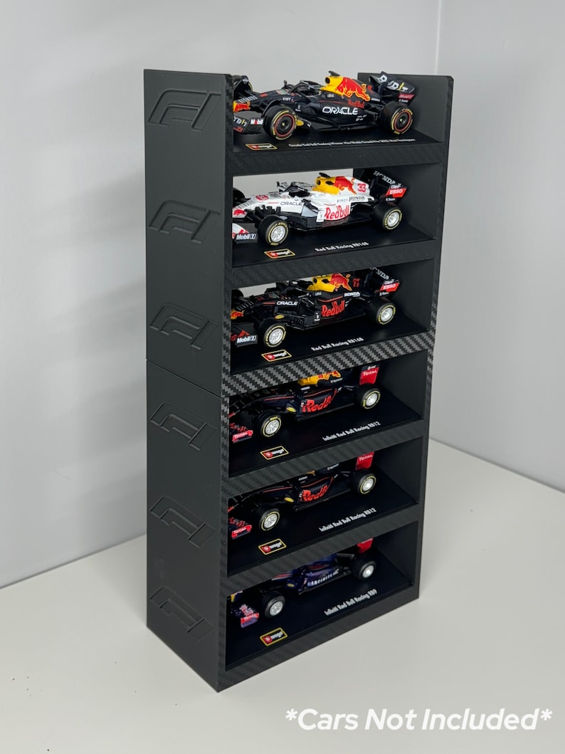 May include: Black and red Formula 1 car display stand with five shelves. The stand is made of black plastic and has a carbon fiber pattern. The shelves are designed to hold 1:18 scale model cars. *Cars Not Included*