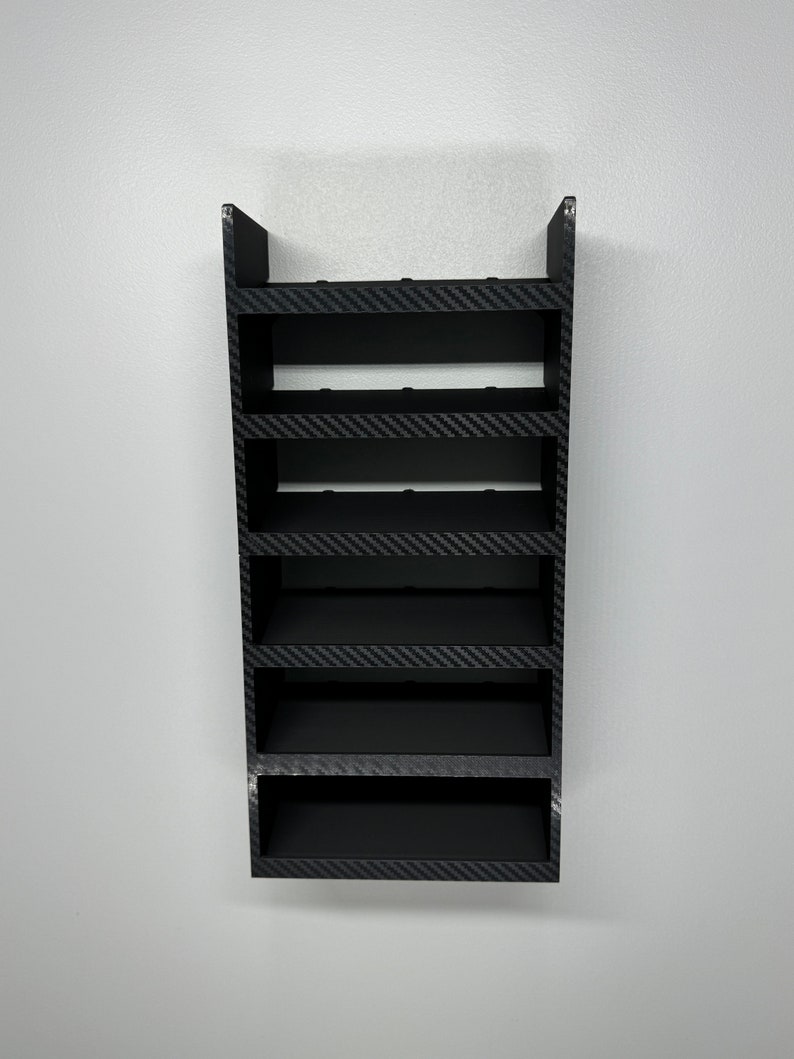 May include: A black wall-mounted shelf with six shelves. The shelves are made of a material that looks like carbon fiber.